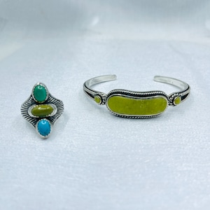 May include: A silver ring with three turquoise stones and a silver bracelet with a yellow stone.