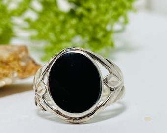 May include: A silver ring with a black oval gemstone set in a delicate floral design.