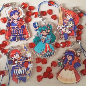 Puede incluir: Conjunto de cinco amuletos de personajes de estilo anime de colores con un personaje de pelo azul sosteniendo un libro, un personaje de pelo rojo sosteniendo una espada, un personaje de pelo verde sosteniendo un ramo de flores, un personaje de pelo rojo sosteniendo una espada y un personaje de pelo marrón sosteniendo un arco y una flecha. Los amuletos están todos sobre un fondo blanco con corazones rojos.