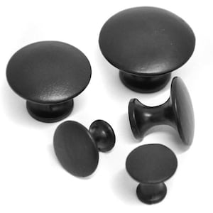 May include: Five black cabinet knobs in different styles and sizes. The knobs are made of metal and have a smooth, matte finish.
