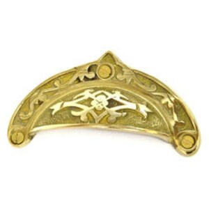 May include: A brass drawer pull with an ornate design. The pull is shaped like a half-moon with a floral pattern in the centre.