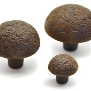 May include: Three brown ceramic cabinet knobs with a swirling pattern. The knobs are of different sizes.