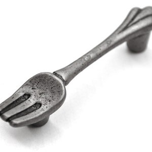 May include: A silver-toned metal cabinet pull shaped like a fork. The handle is smooth and has a slightly curved design.