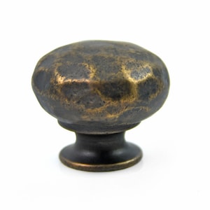 May include: A hammered brass cabinet knob with a distressed finish. The knob has a rounded top and a circular base.
