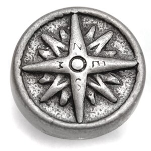 May include: A silver compass with a star-shaped design and the letters N, S, E, and W around the edge.