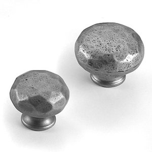 May include: Two silver metal cabinet knobs with a hammered finish. The knobs are round and have a slightly domed shape.