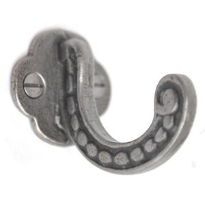 May include: A silver metal hook with a decorative design. The hook has a rounded base and a curved hook.