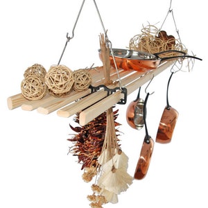May include: A hanging wooden shelf with a metal frame, displaying decorative items. It features small copper pots, dried chillies, and woven spheres. A small copper pan sits on the shelf, adding to the rustic kitchen theme.