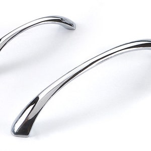 May include: Two polished chrome cabinet door handles with a curved design.