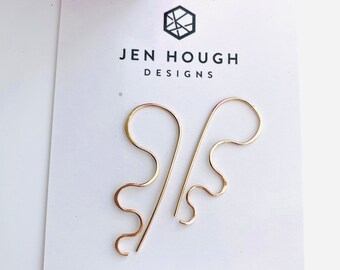 May include: A pair of gold-toned, handmade earrings with a wavy, abstract design. The earrings are displayed on a white card with the text "Jen Hough Designs" and "handmade jewellery www.JenHoughDesigns.com".