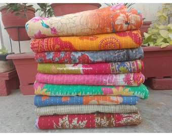 May include: A stack of colorful kantha quilts with floral and geometric patterns. The quilts are made of recycled saris and are perfect for adding a touch of bohemian style to your home.