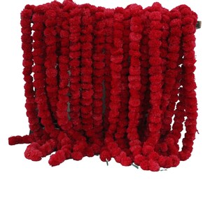 Pode incluir: Uma longa guirlanda de pompons de flores de calêndula vermelhas. A guirlanda é feita de muitos pompons individuais enfiados.