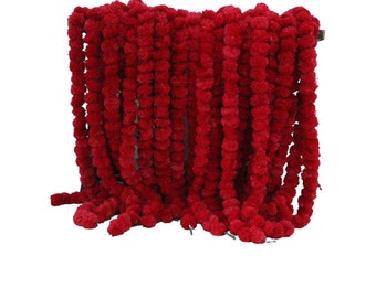 May include: A long garland of red marigold flower pom-poms. The garland is made of many individual pom-poms strung together.