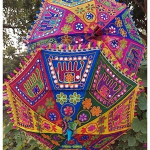 May include: Two colourful Indian umbrellas with intricate embroidery and mirror work. The umbrellas are decorated with hand-painted designs and have a bright yellow, pink, blue, green, and red colour scheme.