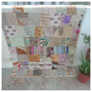 Puede incluir: Una colcha de retazos hecha de varias telas en tonos marrones, beige, rosa y morado. La colcha está cosida a mano y tiene un aspecto rústico y vintage. El texto "copyright@handicraftexports" es visible en la esquina inferior izquierda.