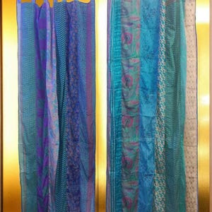 May include: Two sets of colorful curtains made from repurposed fabric. The curtains are a mix of blue, purple, and green tones with various patterns. The curtains are hanging on a rod in front of a gold wall.