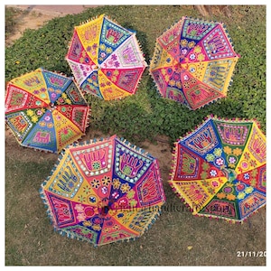 May include: Five colourful umbrellas with intricate embroidery and mirror embellishments. The umbrellas are made of fabric and have a traditional Indian design.