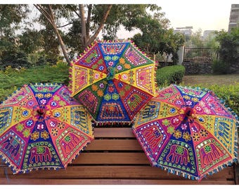 May include: Three colourful umbrellas with intricate embroidery and mirror accents. The umbrellas are decorated with floral patterns and elephants.
