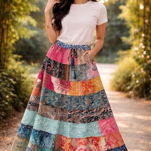 May include: A long, patchwork skirt with a variety of colorful patterns, including paisley and floral designs. The skirt is paired with a white t-shirt. The skirt has a drawstring waist and pockets. The overall style is bohemian.