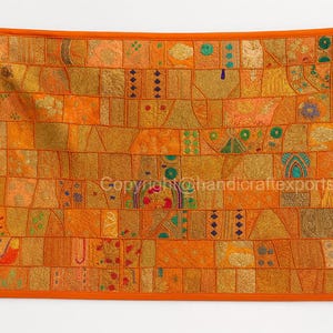 May include: A rectangular, patchwork wall hanging with an orange border. The design features a variety of orange, gold, and peach-colored fabric squares, each with unique patterns and textures. The overall aesthetic is a blend of traditional and bohemian styles.
