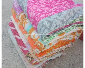 May include: A stack of colorful kantha quilts, featuring a variety of patterns and colors, including pink, orange, green, and blue. The quilts are folded and stacked on top of each other, creating a visually appealing display.
