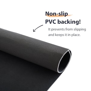Pu&ograve; includere: Primo piano di un tappetino nero arrotolato con un retro in PVC strutturato e antiscivolo. Il testo recita: "Non-slip PVC backing! It prevents from slipping and keeps it in place."
