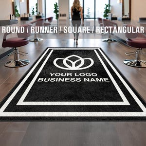 Puede incluir: Alfombra de bienvenida negra con borde blanco y un logotipo blanco de flor estilizado. El texto "YOUR LOGO BUSINESS NAME" está impreso en blanco en la alfombra.