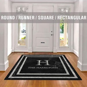 May include: Black and white square doormat with a marble pattern and a white border. The doormat has the letter "H" and the text "The Hamiltons" in white.