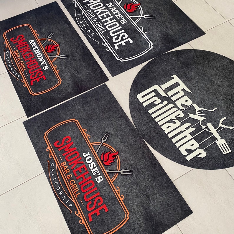 Pu&ograve; includere: Una collezione di tappeti neri rettangolari e circolari con loghi di ristoranti. I tappeti presentano i nomi "Nate's Smokehouse", "Anthony's Smokehouse", "Jose's Smokehouse" e "The Grillfather" in testo bianco e rosso.