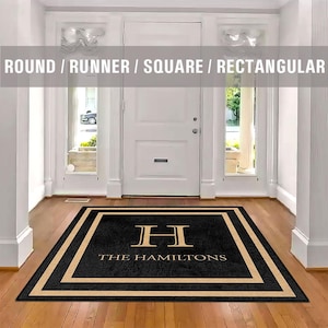May include: Black and white doormat with a gold border and the text "The Hamiltons" and a gold "H" monogram.