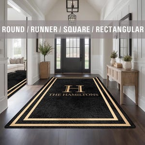 May include: Black doormat with a gold border and the text "THE HAMILTONS" in gold lettering with a gold "H" monogram.