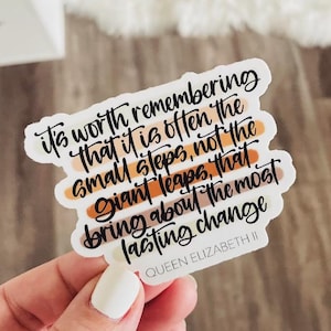 May include: A white sticker with black cursive text that reads "It's worth remembering that it is often the small steps, not the giant leaps, that bring about the most lasting change." The text is above the words "QUEEN ELIZABETH II."
