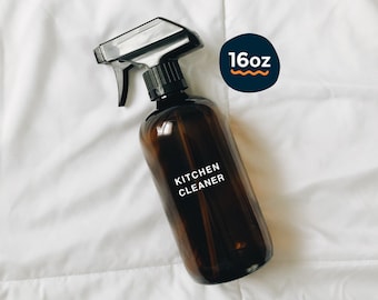 May include: A brown glass spray bottle with a black trigger sprayer. The bottle is labeled "Kitchen Cleaner" and has a sticker that says "16oz".
