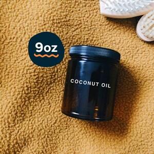 Könnte beinhalten: Ein 250 ml Glasgefäß mit Kokosöl und einem schwarzen Deckel. Das Gefäß steht auf einer braunen, flauschigen Oberfläche.
