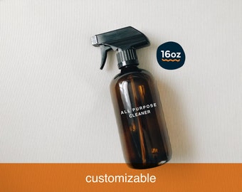 May include: A brown glass spray bottle with a black trigger sprayer. The bottle has a white label that says "ALL PURPOSE CLEANER". The bottle is sitting on a white surface. The bottle is 16 ounces.