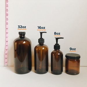 May include: Four amber glass bottles with black pump tops and a smaller amber glass jar with a black lid. The bottles are labeled 32oz, 16oz, and 8oz. The jar is labeled 9oz.