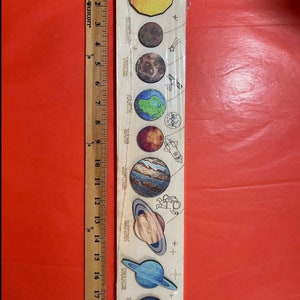 Puede incluir: Una tabla de madera con una ilustraci&oacute;n colorida de los planetas de nuestro sistema solar. Los planetas est&aacute;n etiquetados con sus nombres: Mercurio, Venus, Tierra, Marte, J&uacute;piter, Saturno, Urano y Neptuno. La tabla mide aproximadamente 45,7 cm de largo.