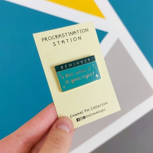Pode incluir: Um pin de esmalte da cole&ccedil;&atilde;o "Procrastination Station". O pin retangular tem um fundo verde-azulado com o texto "But what if it goes right?" e a palavra "REMINDER" acima. O pin est&aacute; em um cart&atilde;o amarelo claro.