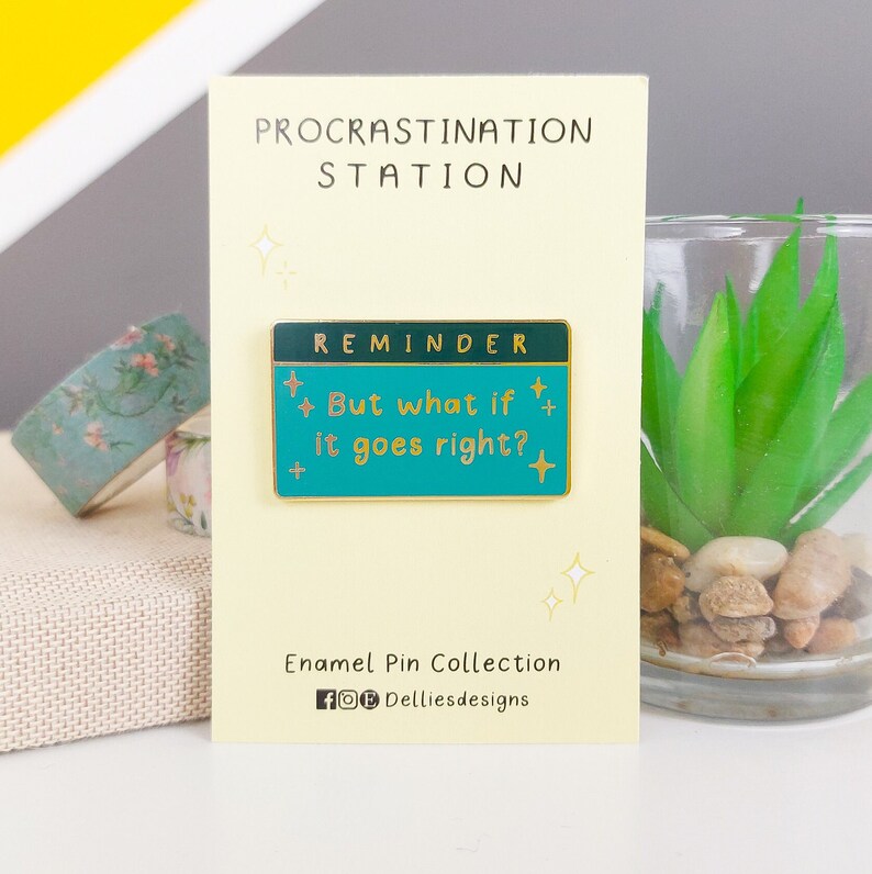 Pode incluir: Um alfinete de esmalte turquesa com o texto "But what if it goes right?" e a palavra "REMINDER" no topo. O alfinete est&aacute; em um cart&atilde;o creme com as palavras "PROCRASTINATION STATION" no topo. O cart&atilde;o tamb&eacute;m inclui o texto "Enamel Pin Collection".