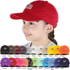 May include: A collection of 15 baseball caps in various colors, each featuring a small embroidered American flag on the front. The caps are arranged in three rows of five, with the colors ranging from black, brown, burgundy, charcoal grey, white, putty, khaki, yellow, gold, orange, purple, red, hot pink, coral, woodland camo, lime, aqua, turquoise, sky blue, royal blue, and navy.