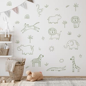 May include: A white wall decorated with green line drawings of safari animals, including a lion, zebra, giraffe, and elephant. Other drawings include a flamingo, palm trees, and a sun. The wall is in a child's room with a shelf, basket, and stuffed animals.