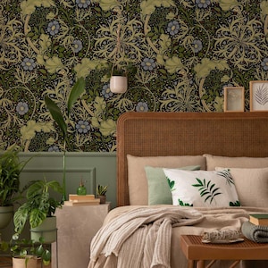 May include: A bedroom interior with floral wallpaper in dark tones, green and blue floral patterns. The bed has a woven headboard, beige bedding, and decorative pillows. Plants and framed pictures enhance the room's aesthetic.