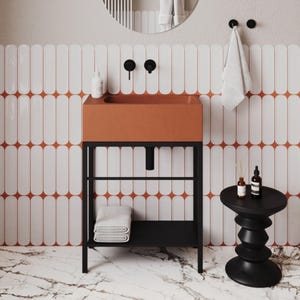 May include: A contemporary bathroom vanity featuring a terracotta sink and a black metal frame. The sink is above a black shelf with folded white towels. The background has white tiles with an orange pattern.