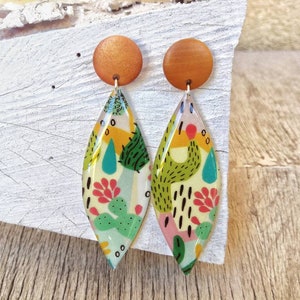 Pop style earrings handmade in resin, with design of plants and cacti. Button closure in wood and stainless steel. Length 7.5 cm.