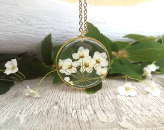 Resin pendant with spirea flower. Golden edge, diameter 3 cm. Thin gold-colored stainless steel chain.
