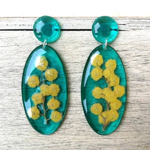 May include: Teal oval earrings with a pressed yellow flower design.