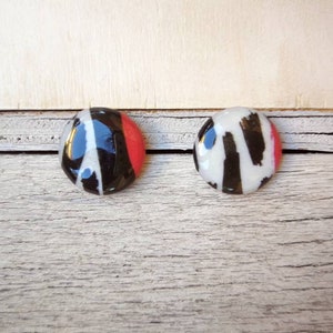 Small stud earrings with a black and coral brushstroke design. Diameter 1.5cm. Stainless steel pin closure with butterfly.