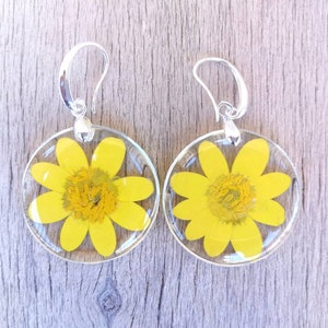 May include: A pair of silver earrings with yellow flower pressed inside clear resin.