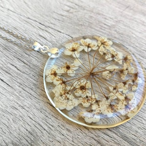 Pendant with pressed white flower. In transparent resin, handmade. Thin chain 50 cm. Diameter of the pendant 4 cm.