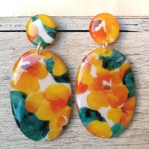 Orecchini ovali in resina, con motivo floreale arancio e verde. Chiusura a perno in acciaio inox con farfallina. H6xL2,8cm